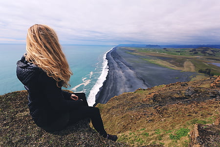 woman sitting on the rock facing on the seashore thumbnail
