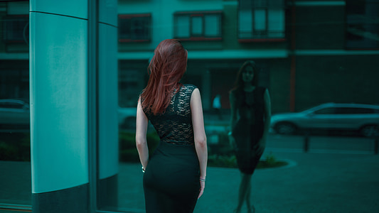 woman in black dress standing near black wall glass thumbnail