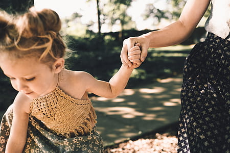 person in black dress holding girl's hand outside thumbnail