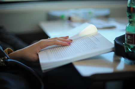person's hand holding opened black print white book thumbnail
