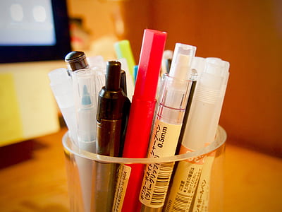 assorted-color pens on clear glass container thumbnail