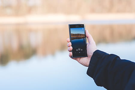 Man taking photo of a lake with mobile phone thumbnail