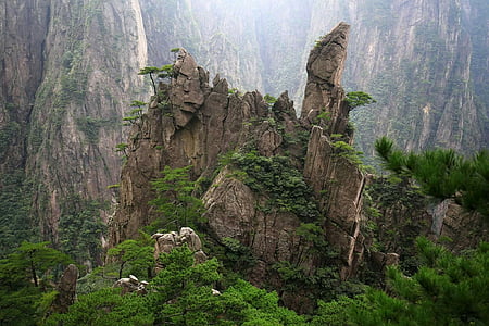 brown rock formation with trees under a mountain at daytime thumbnail