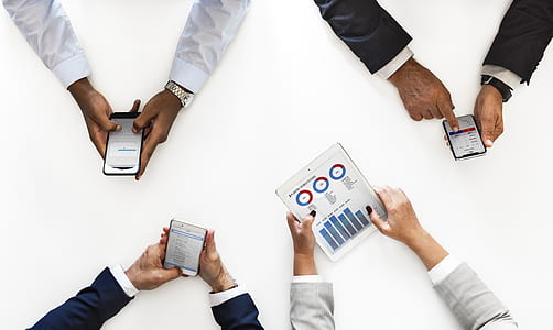 top view photo of three four person holding mobile gadgets thumbnail