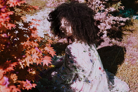 woman wearing white floral dress beside red plant during daytime thumbnail