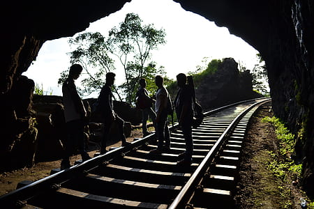 five persons standing on railway inside tunnel thumbnail
