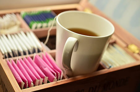 white ceramic mug with tea in brown wooden tea bag box thumbnail