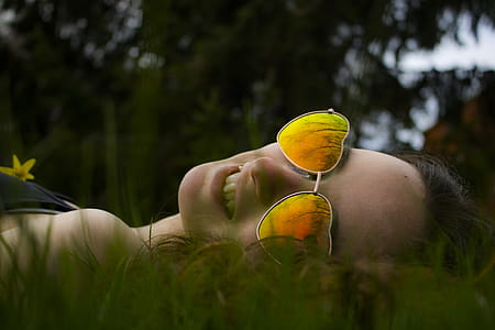Lying Woman on Green Grasses With Gold-colored Sunglasses Closeup Photo thumbnail
