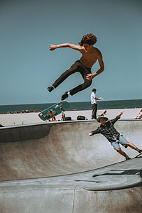 topless man using skateboard near beach under clear sky thumbnail