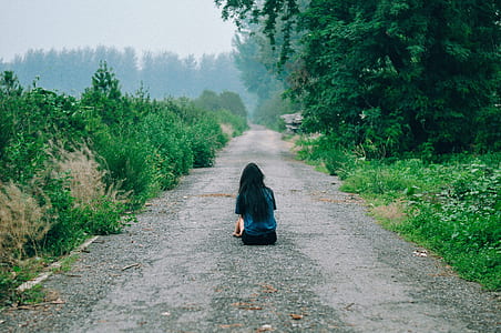 girl in blue shirt sitting on road during daytime thumbnail