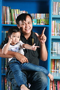 man in black collared top and blue jeans carrying boy in white crew-neck shirt and blue jeans thumbnail