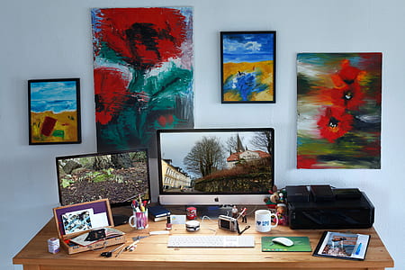silver iMac beside keyboard and paintings thumbnail