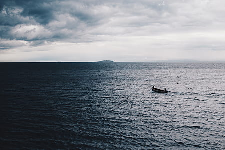 rowboat on calm body of water under white cloudy sky at daytime thumbnail