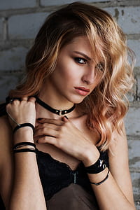 woman looking straight to the camera while holding her collar bone thumbnail