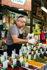 man in gray shirt with black apron holding pack of green powder thumbnail