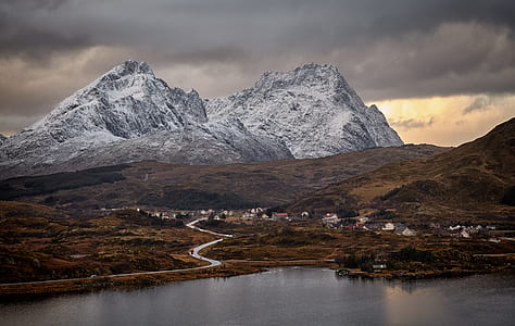 village near snow-capped mountain and body of water thumbnail