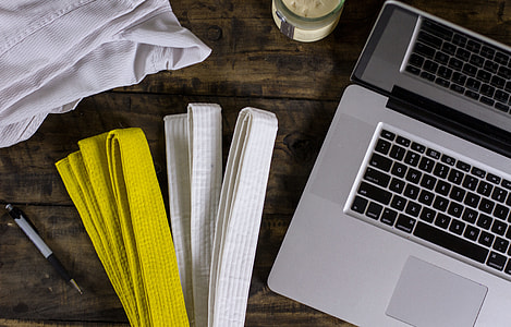 yellow and white Karate Gi belts beside MacBook Pro on top of table thumbnail