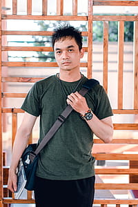 Man Holding Crossbody Bag Standing on Outdoors thumbnail