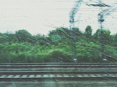 water droplets on moving train's window with blurry forest background thumbnail