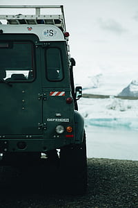 green Land Rover Defender on asphalt road thumbnail