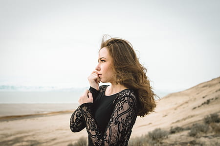 woman holding her wrist white standing and looking at the distance thumbnail