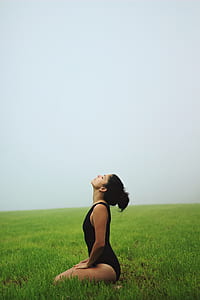 woman sitting on grass field under white clouds thumbnail