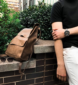 person leaning beside brown leather backpack and sunglasses thumbnail