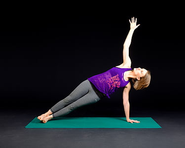 woman wearing purple tank top and gray leggings with and yoga position on green yoga mat thumbnail