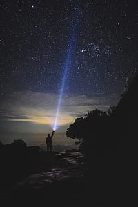 silhouette of person holding torch pointing to sky at night thumbnail