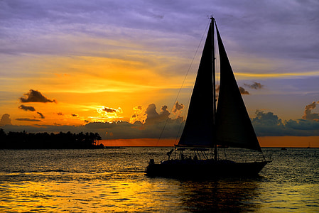 silhouette of sailboat on ocean water during orange sunset thumbnail