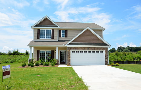 beige 2-storey house with garage under blue sky during daytime thumbnail