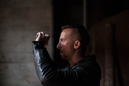 man in black leather jack holding device thumbnail