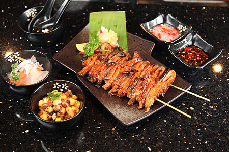 skewered meat dish on platter with side dish and sauce thumbnail