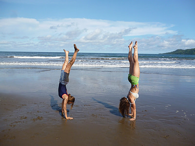 two women standing on hands at the seashore thumbnail