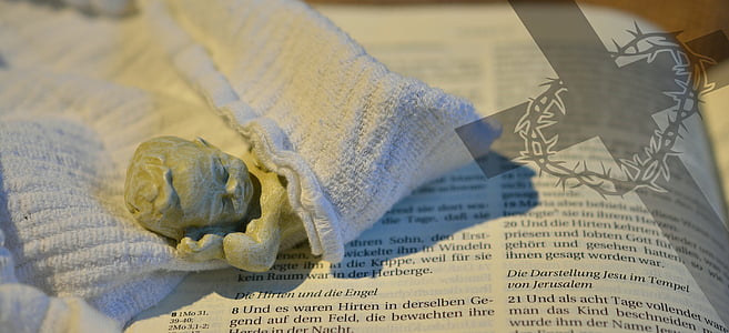 lying baby figurine in white cloth on book page thumbnail