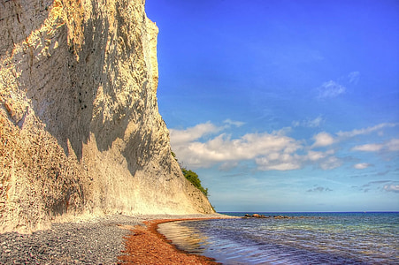 beige cliff beside body of water at daytime photo thumbnail