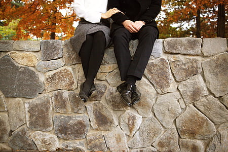 man and woman sitting on top of concrete wall thumbnail