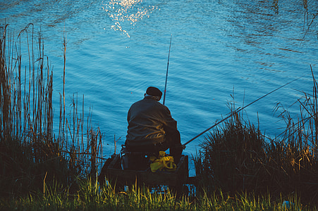 person fishing while sitting near grass during daytime thumbnail