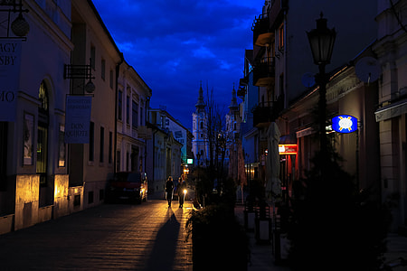 people walking between concrete buildings during nighttime thumbnail