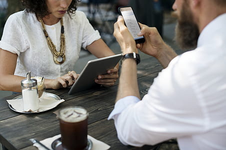man holding phone in front of woman holding tablet computer thumbnail