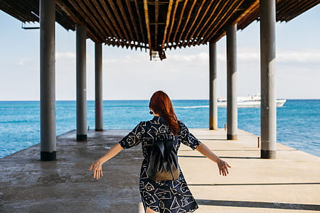 woman standing on dock near body of water thumbnail