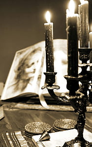 sepia photography of lighted candles with candelabra near open books thumbnail