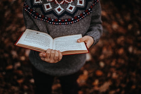 selective focus photo of person holding open book thumbnail