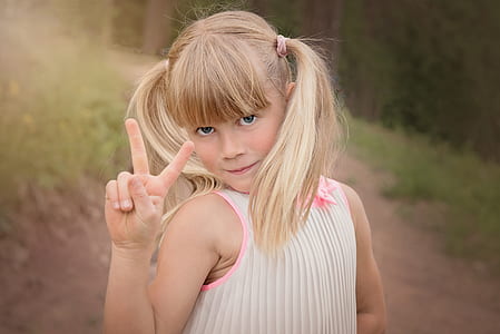 girl standing on pathway while making peace sign thumbnail