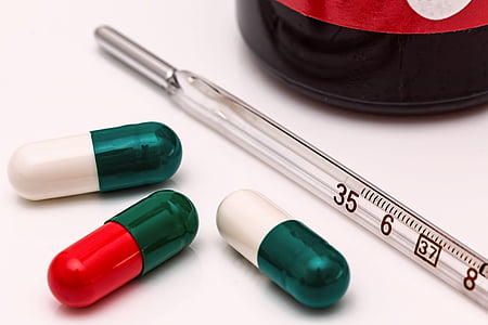 person taking photo of three medication capsules with thermometer thumbnail