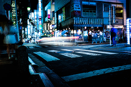 timelapse photography of white and black concrete road beside concrete buildings with lights thumbnail