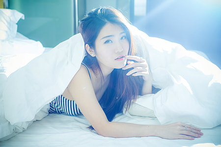 Beautiful Asian girl in bed in the sunlight thumbnail