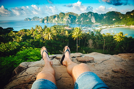 person sitting on mountain cliff during daytime thumbnail