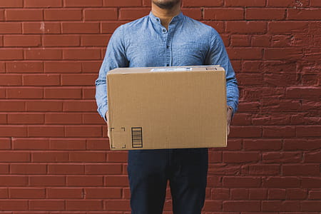 Man Holding Shipping Box On Red Brick Photo thumbnail