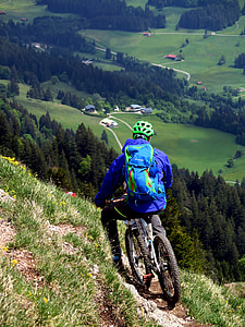selective focus photo of person wearing blue jacket riding bicycle at daytime thumbnail